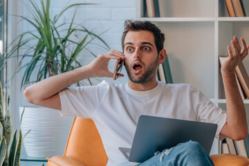 man at home talking on mobile phone with surprised expression