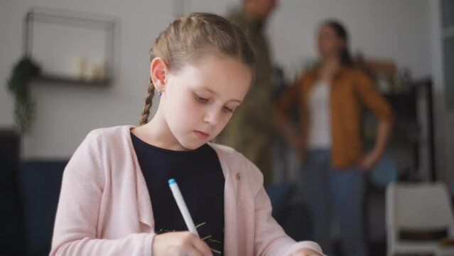 Diligent little girl drawing picture, parents arguing in background, divorce