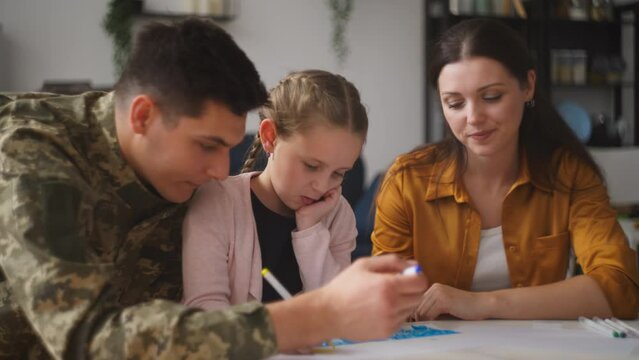 Military father and mother drawing together with little daughter, family time