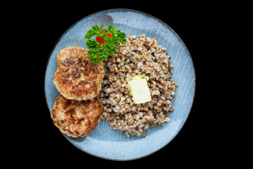 buckwheat with meat cutlets on a black background top view