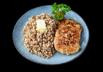 buckwheat with meat cutlets on a black background top view