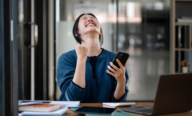 successful and exciting  businesswoman. Young woman excited to win on her smartphone at work.