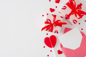 Valentines Day concept. Flat lay composition made of gift boxes, envelope with letter, heart shaped lollipop and sprinkles on white background with copy space.
