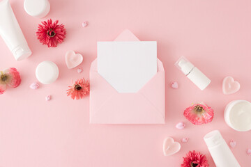 Women day concept. Creative layout made of cosmetic bottles, heart shaped candles and spring flowers on pastel pink background with envelope with letter in the middle. Mother's day celebration idea.