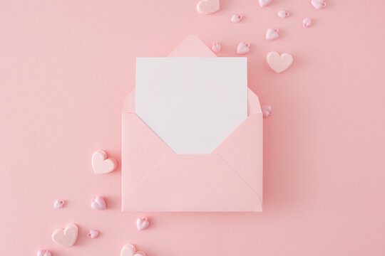 Valentines Day Concept. Flat Lay Composition Of Pink Heart Shaped Baubles On Pastel Pink Background And Envelope With Letter In The Middle. Lovers Holiday Card Idea.