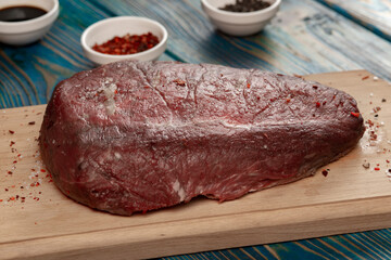 raw beef steak with vegetables and spices on wooden table
