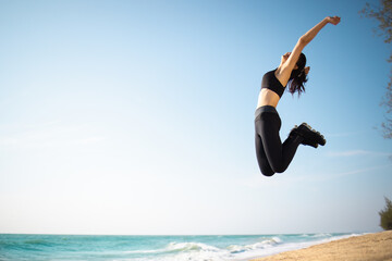 Athlete sport female happy jumping exercise workout on the beach in day time, Wellness, training and warm up athlete on the coast to start running