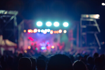 Silhouettes of concert crowd with stage lights, out of focus blurred photo