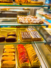 In the candy store counter with cakes. Pastry shop glass display with selection of cream or fruit cake