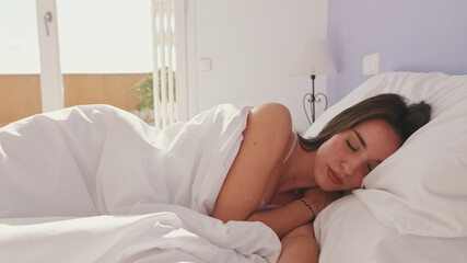 Young woman sleeping in bed early in the morning