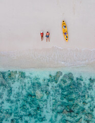 drone view at couple laying down on the beach of Koh Phi Phi Thailand during vacation with kayak.