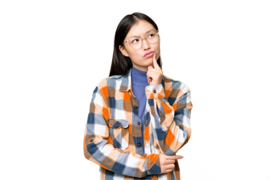 Young Asian woman over isolated chroma key background having doubts while looking up