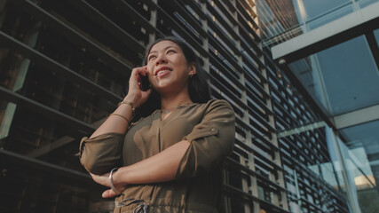 Young businesswoman talking on smartphone on business center background