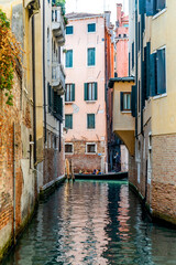 Fototapeta na wymiar A narrow canal in Venice, near Sotoportego degli Armeni, with a gondola and tourists in the background, Venice city center, Veneto region, Italy