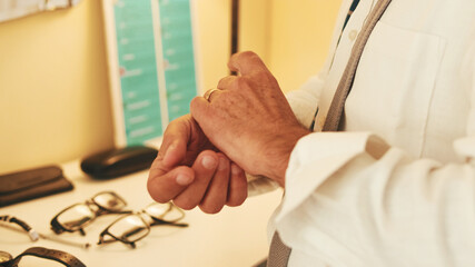 Obraz premium Close-up of the hands of middle-aged man putting on wristwatch while standing in front of mirror