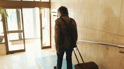 Middle aged man leaving home with luggage