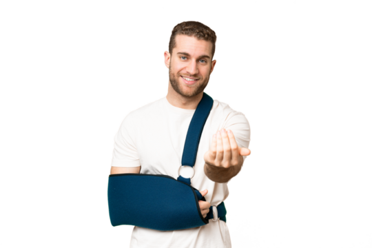 Young handsome blonde man with broken arm and wearing a sling over isolated chroma key background inviting to come with hand. Happy that you came