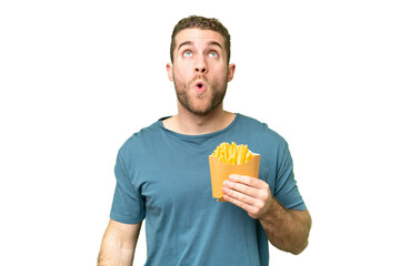Young handsome blonde man holding fried chips over isolated chroma key background looking up and...