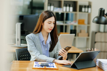 Fototapeta premium Confident Asian woman with a smile standing holding notepad and tablet at the modern office..