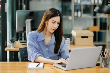  beautiful woman typing on tablet and laptop while sitting at the working wooden table modern office.