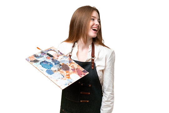 Young artist woman holding a palette over isolated chroma key background laughing in lateral position