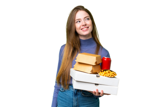 Young pretty woman holding pizzas and burgers over isolated chroma key background thinking an idea while looking up