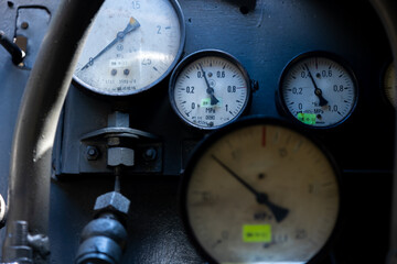 A set of pressure gauges and other gauges on a steam locomotive boiler. Interior of a steam locomotive kiosk.
