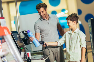 Father and son buying food at grocery store or supermarket self-checkout