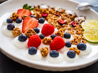 Yogurt with strawberries, blueberries, raspberries and muesli in bowl on wooden table
