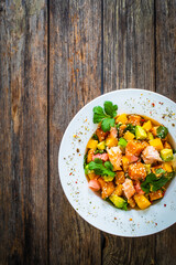 Salmon ceviche with lemon, mango and avocado on wooden table