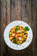 Salmon ceviche with lemon, mango and avocado on wooden table