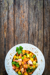 Salmon ceviche with lemon, mango and avocado on wooden table