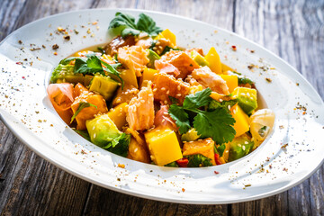 Salmon ceviche with lemon, mango and avocado on wooden table