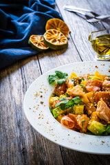 Salmon ceviche with lemon, mango and avocado on wooden table