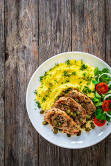 Fried pork loin with mashed potatoes and vegetables on wooden table

