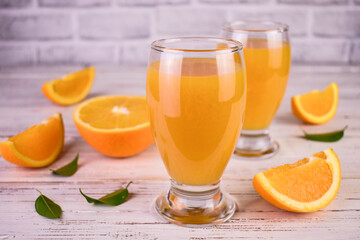 Orange juice in glasses on a white wooden background.
