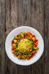 Fried chicken nuggets, bulgur groats, carrots and red pepper on wooden background
