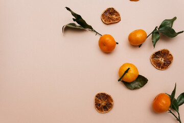 A composition of tangerines and dried candied fruits lie on a beige background. Christmas theme