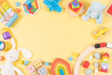 Baby kids toy frame background. Wooden, plastic, educational, musical, sensory, sorting and stacking toys for children on yellow background. Top view, flat lay, copy space
