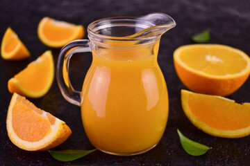 Fototapeta na wymiar Orange juice in a glass decanter on a black background.Close-up. 