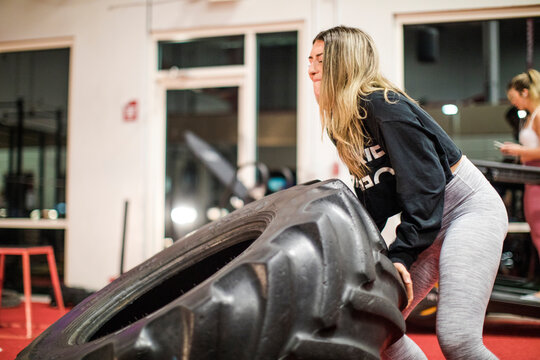 Woman working out in gym using heavy tire