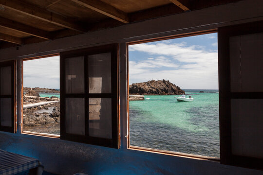 Window frames with clear blue ocean and a boat outside