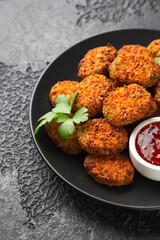Carrot and spinach vegan vegetarian bites with sweet chili sauce in a black plate