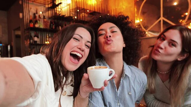 Group of three happy young women taking a selfie portrait on a coffee shop. Multi ethnic friends taking a photo smiling and looking at camera. High quality photo