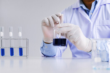 Science innovative Male medical or scientific laboratory researcher performs tests with blue liquid...