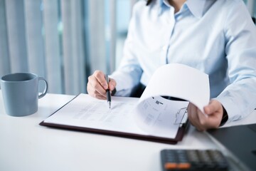 Portrait of  Asian Business woman working from office taking reading and writing notes in note pad working on laptop computer  in her workstation