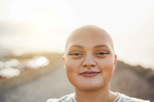 Happy bald girl smiling in front of camera outdoor - Focus on nose