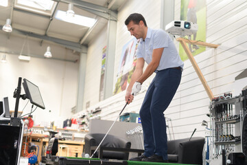 man testing golf club in a shop