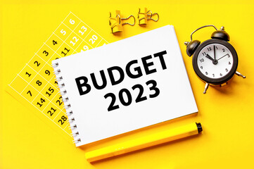 2023 budget text. black alarm clock on yellow background.