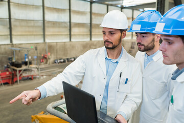businessman and engineers working with laptop in factory